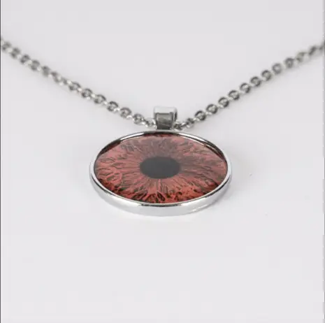 Close-up of a pendant featuring a custom iris photo encased in glass, showcasing the intricate details of the eye